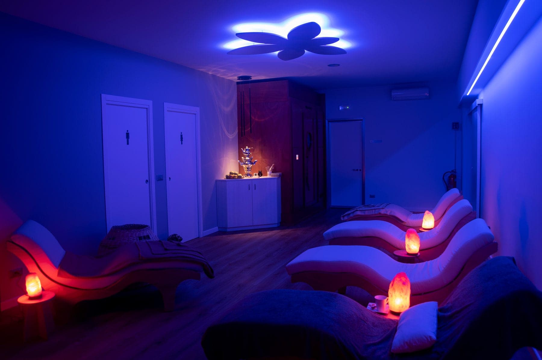 Sala relax dell'area SPA con lettini ergonomici, lampade di sale e luce blu soffusa